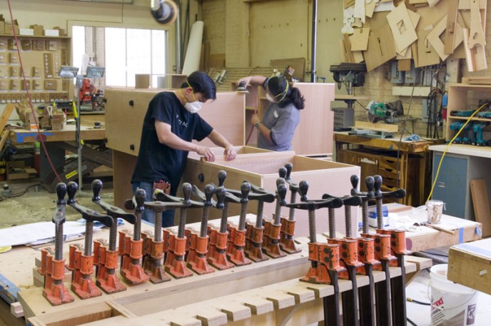 Workers assembling parts for custom cabinets.